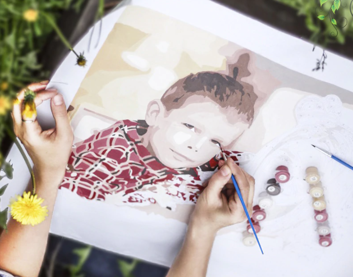 Photo of a young boy that is being painted by his mother